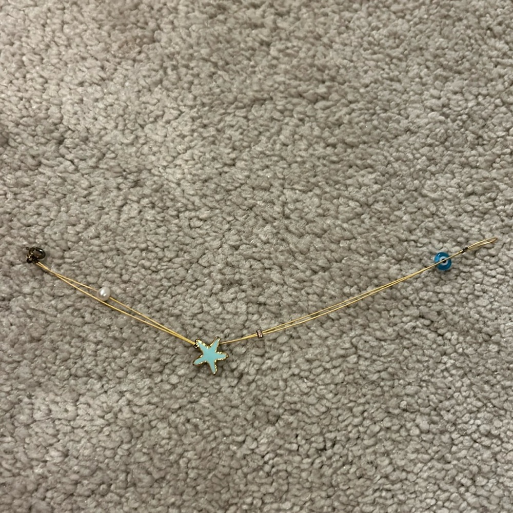 Bracket w a blue starfish charm, a pearl charm, and an evil eye charm